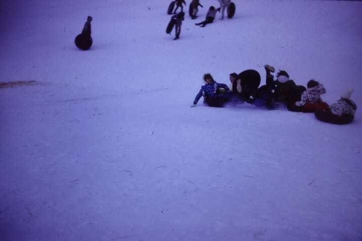 an out of focus image of children sledding on a snowy hill
