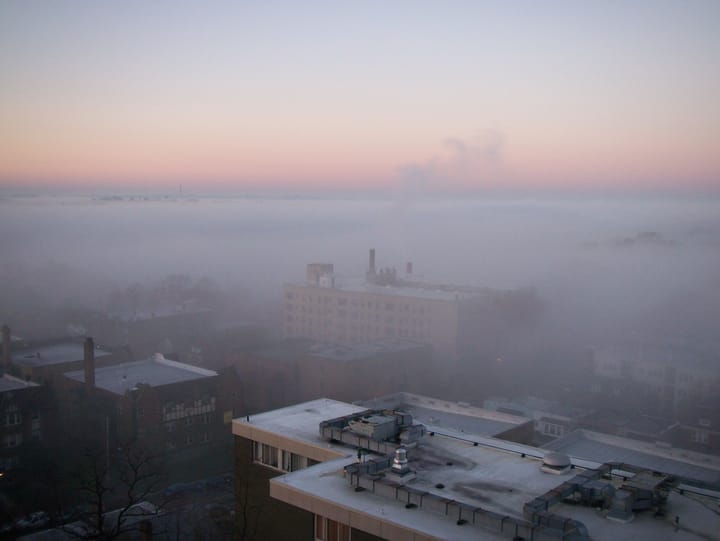 view of a cityscape partly obscured by fog, pink horizon