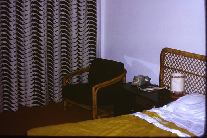 snapshot of a hotel room showing part of the bed and a chair and table