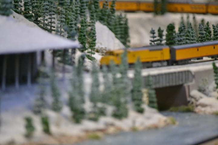 Out of focus photo of a model train in a forest landscape with bridge